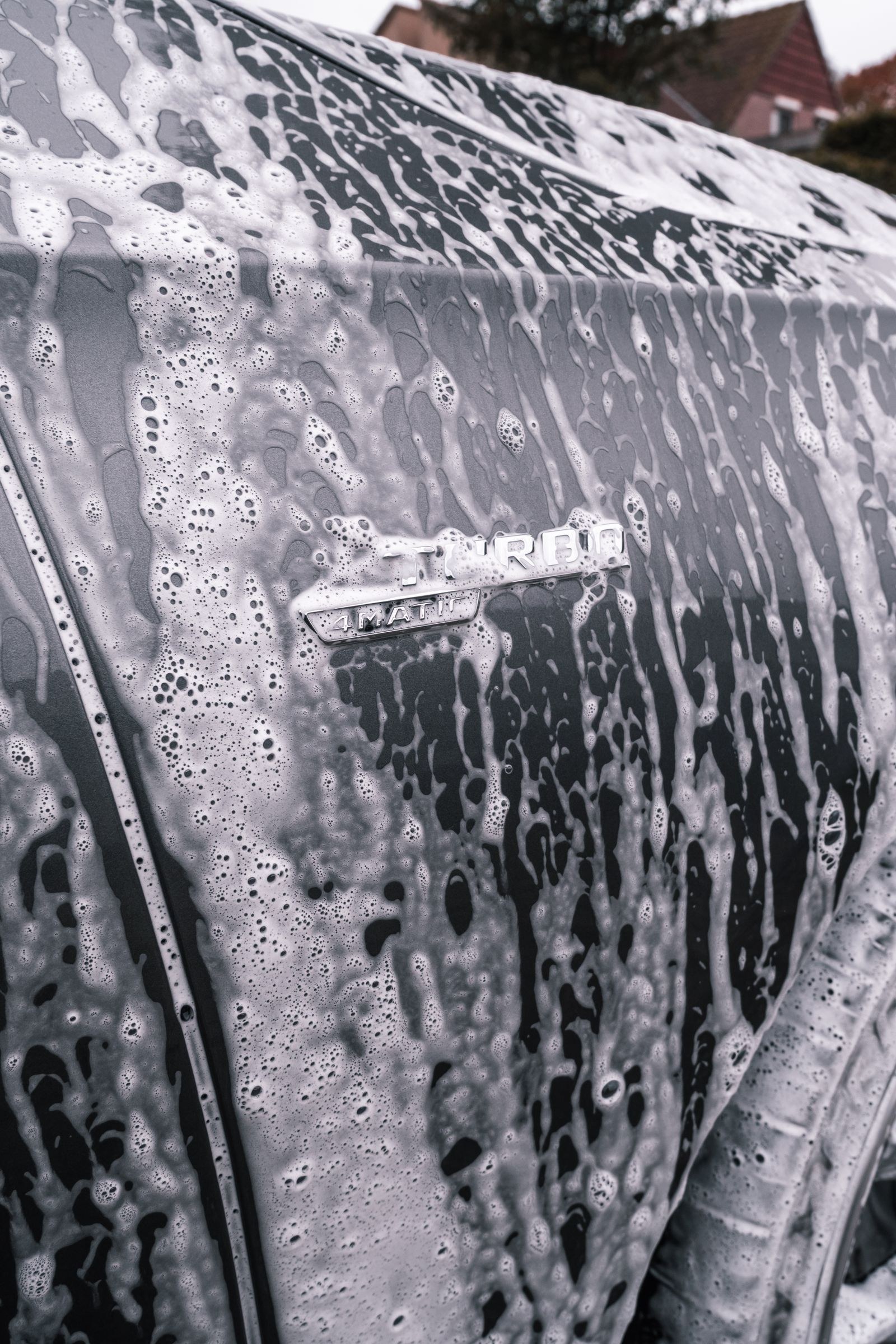 Close-up of a car's exterior covered in wash suds during a hand wash